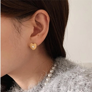 Detailed close-up of a vintage-style gold heart stud earring with a central zircon stone