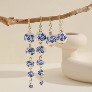 Elegant blue and white porcelain drop earrings with gold hooks on a natural wooden branch