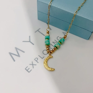 Detailed macro view of French vintage moon pendant with green beads on 18k gold chain