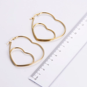 Golden heart-shaped hoop earrings in titanium steel shown with a scale ruler for sizing