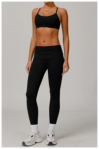Detail of high-waist ruched leggings and strappy sports bra in black quick-dry fabric