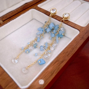 Détail des boucles d'oreilles à pompon en cristal bleu clair sur un écrin à bijoux en bois