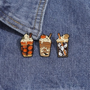 Détail de broches d'Halloween en émail avec motifs citrouille et fantôme sur denim bleu