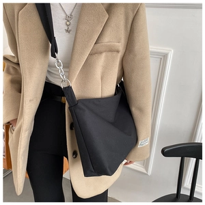 Detailed view of black canvas crossbody bag with silver buckle worn by a model