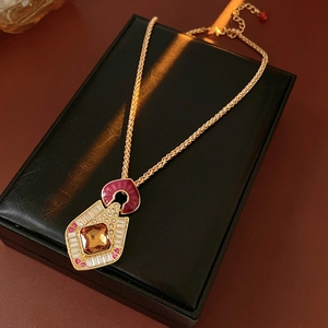 Macro detail of vintage gold necklace with enamel shield pendant on black leather