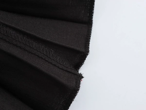 Close-up of black pleated fabric texture and professional stitching on the dress