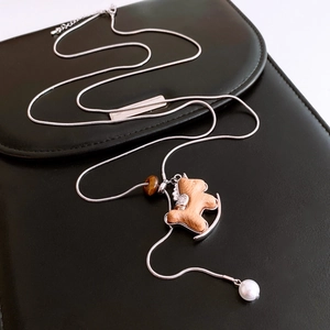 Detail of wooden rocking horse pendant with silver metal frame and pearl on snake chain