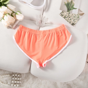 Nahaufnahme orangefarbene Sportshorts mit weißem Saum und Gummizug auf Plüschfläche