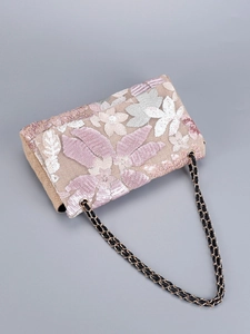 Close-up of floral embroidery and shiny sequins on a woven jute shoulder bag surface