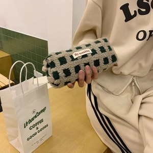 Detail of checkered sherpa pencil case in green and white with side brand label