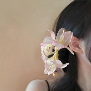 Side view of elegant gradient pink lily flower hair claw clip worn on a low bun