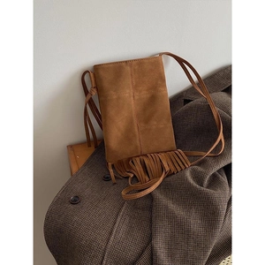 Brown bohemian fringe crossbody bag in matte suede leather on a textured blazer
