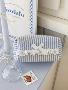 Détail d'une trousse matelassée à rayures bleues avec bordure en dentelle et nœud