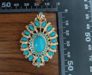 Detail view of ethnic hollow geometric brooch with turquoise stones and 55mm ruler measure