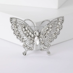 Macro shot of silver butterfly brooch with white rhinestones on geometric stone block