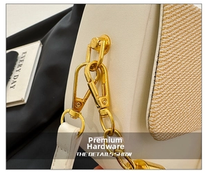 Macro shot of polished gold metal hardware and chain on a textured box handbag
