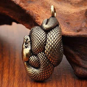 Dettaglio di un ciondolo a serpente in ottone vintage con squame su legno scuro