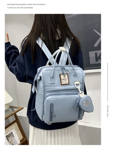 Rear view of light blue maternity backpack with heart charm in a home setting