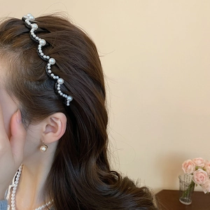 Detail showing wavy pearl headband with white pearls and black base on a model