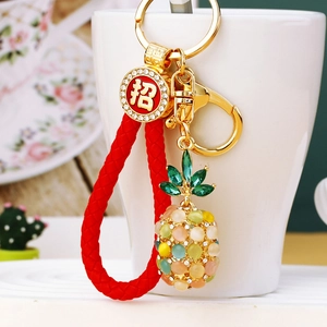Macro detail of pineapple keychain with multicolor gems and red braided rope ornament