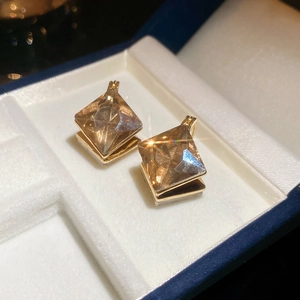 Macro shot of champagne diamond rhombus clip earrings on a white velvet jewelry box