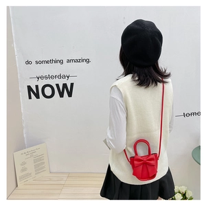 Lifestyle shot of red mini bow purse worn over a white vest and black skirt