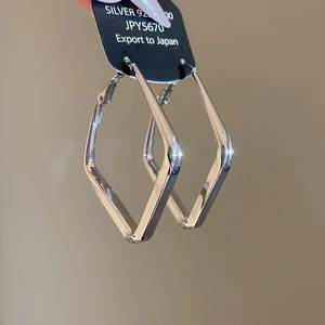 Close-up of polished S925 silver rhombic earrings with mirror-like metallic shine