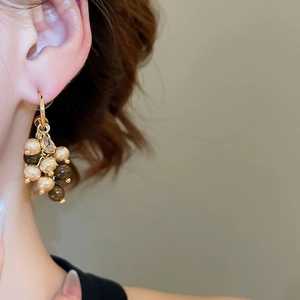 Detail of beaded tassel earrings with gold metallic finish and brown tiger eye stones