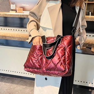 Close-up of wine red quilted tote bag with glossy finish and striped canvas straps