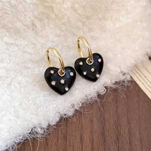 Detail of vintage heart earrings with black enamel and diamonds on soft white fur