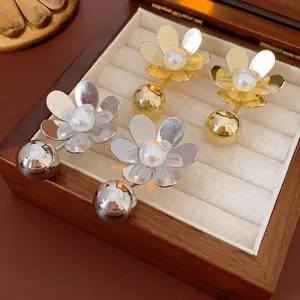 Élégantes boucles d'oreilles fleurs en or et argent avec perles dans une boîte à bijoux