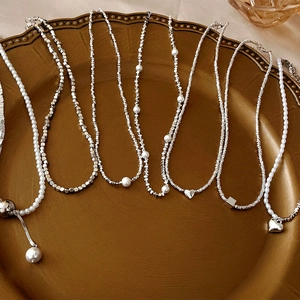 Elegant silver necklaces with pearls and heart pendants on a vintage bronze tray