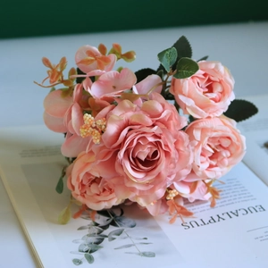 Pink silk roses and peonies bouquet resting on an open book for vintage home decor