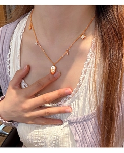 Détail du collier en nacre plaqué or 18 carats avec breloques étoiles sur mannequin