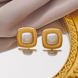 Macro detail of vintage gold square earrings with pearl inlay and spiral texture