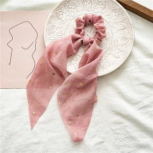 Detailed close-up of pink chiffon hair scrunchie with gold stars on white porcelain plate