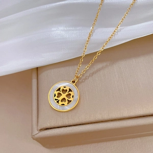 Macro shot of gold four-leaf clover necklace with white shell inlay on jewelry box