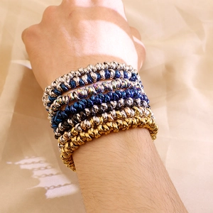 Close-up of metallic spiral elastic bracelets in gold, silver, and blue on a wrist