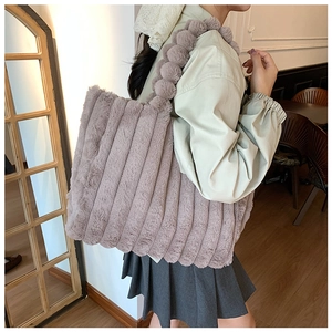 Detailed side view of a smoky pink plush tote bag with striped texture and pom-pom strap