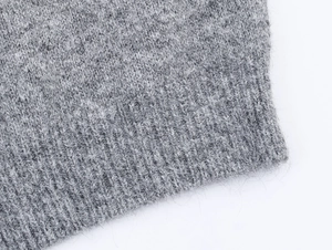 Détail macro du pull en maille gris montrant la texture douce en laine et la finition soignée