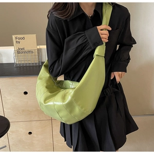 Detail of light green crescent saddle bag with wide shoulder strap and knot decoration