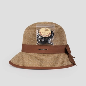 Detail of straw sun hat featuring dark brown ribbon, elegant bow and UPF 50+ rating tag