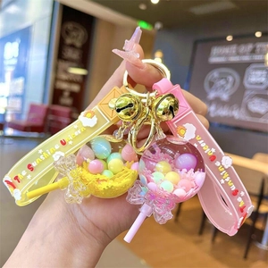 Primo piano di portachiavi unicorno liquidi gialli e rosa con ciondoli colorati in mano