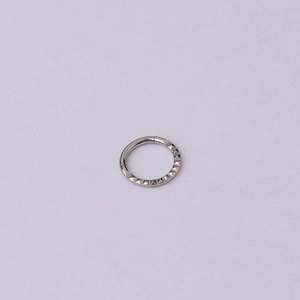 Macro detail of silver stainless steel septum ring with textured pyramid spikes design