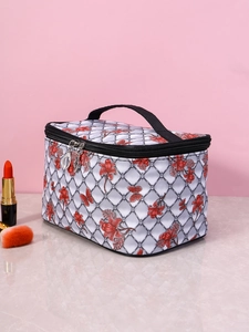 Detail view of floral print cosmetic bag with black handle and zipper on marble surface