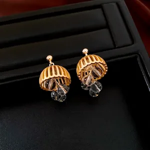 Vintage gold crystal tassel earrings with bell-shaped hollow design on black leather
