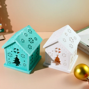 Detailed view of mint green and white ceramic Christmas house luminaries with snowflake cutouts