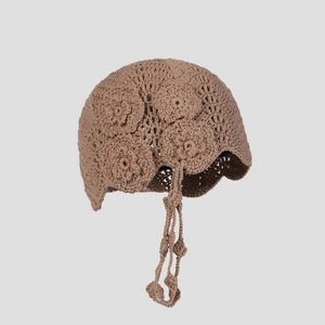 Detail of handmade crochet beanie featuring 3D floral textures and long tasseled straps