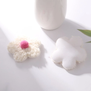Close-up of white plush fabric flowers with pink center on minimalist white background