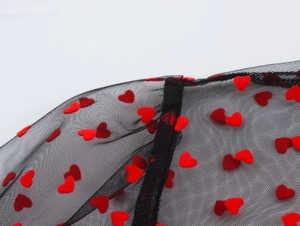 Detailed close-up of heart flocking on mesh shoulder with delicate ruffle lantern sleeves